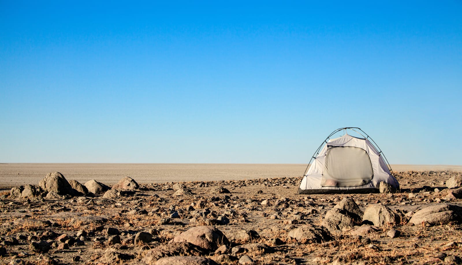 Kuppelzelt auf steinigem Grund über der weiten Makgadikgadi-Pfanne